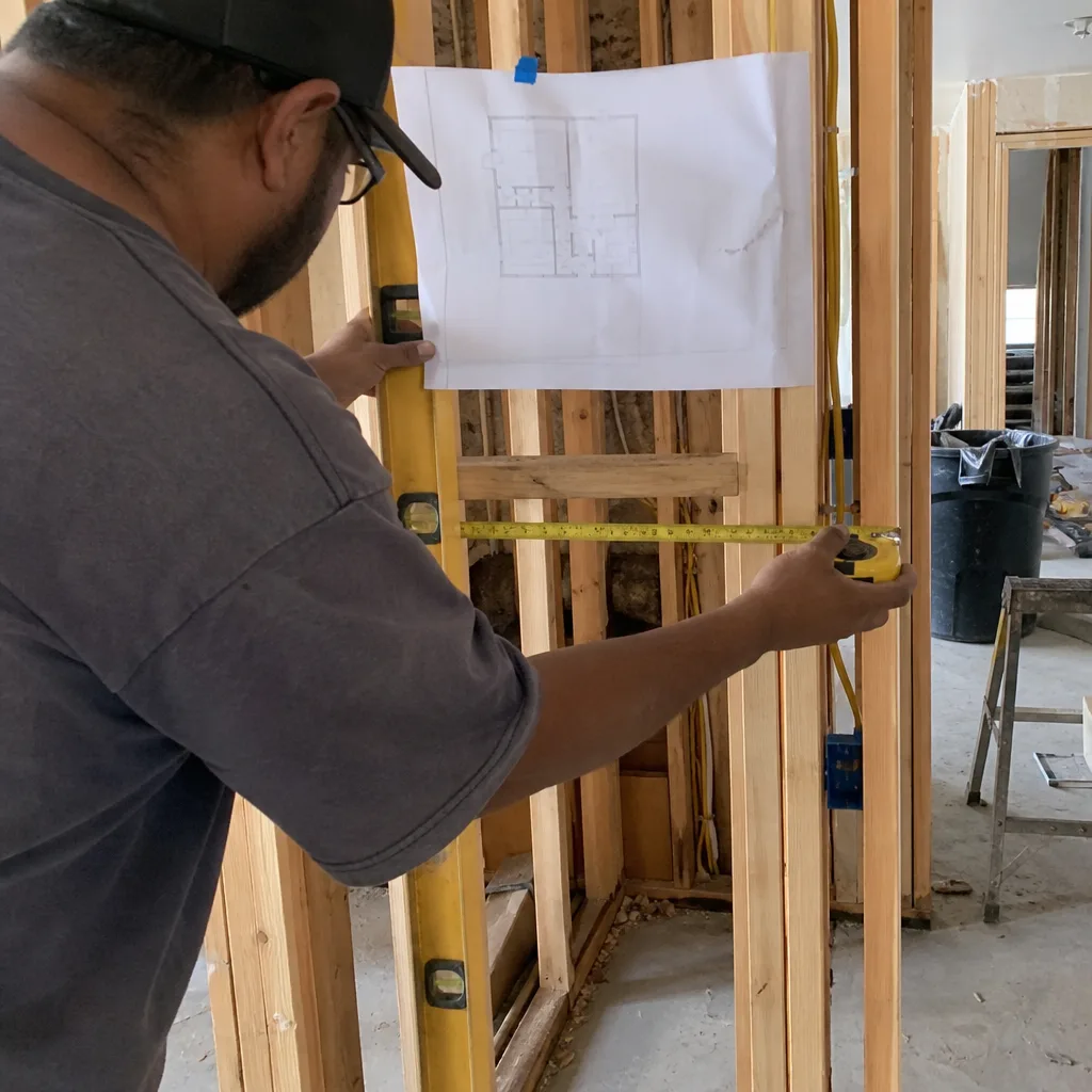 General contractor measuring wall framing during home construction project